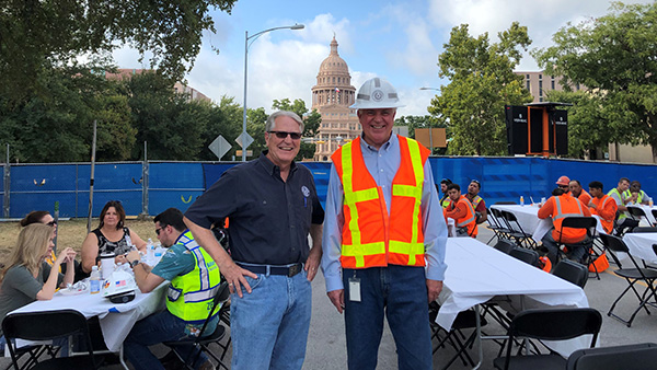 Mike Novak and Former Deputy Director John Raff attend the bottoming out celebration for Phase I of the Capitol Complex with a view of the Texas State Capitol in the background. 
