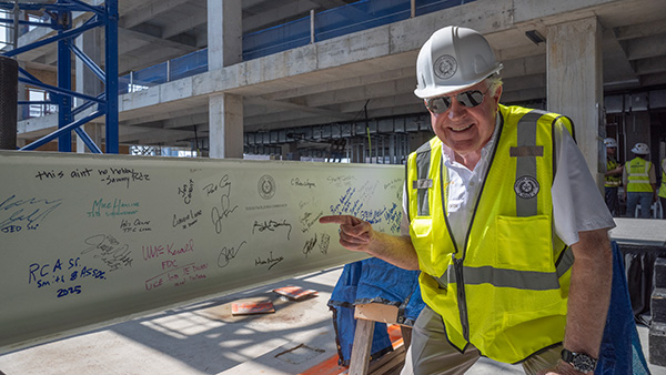 Novak points at the signed beam before it is placed at the topping out ceremony for Phase Two of the Capitol Complex Project. 